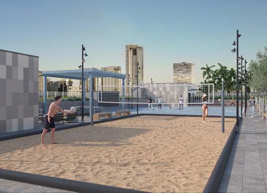 A man is playing beach volleyball in a sandy area with a city skyline in the background.
