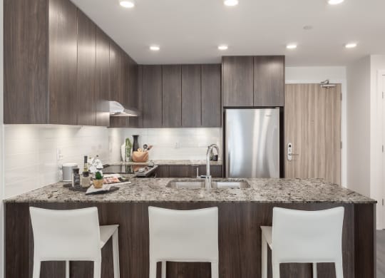 a kitchen with a granite counter top and a stainless steel refrigerator