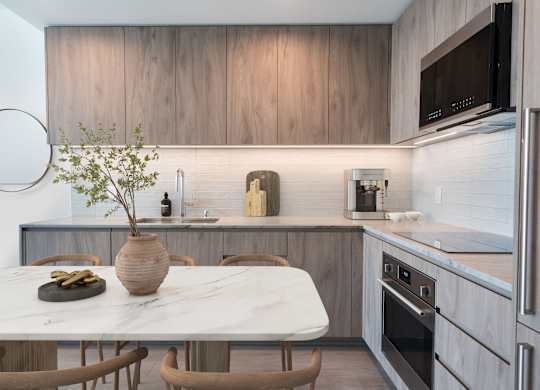 A kitchen with a marble table and wooden chairs.