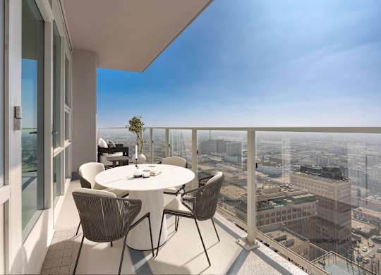 A balcony with a table and chairs overlooking a cityscape.