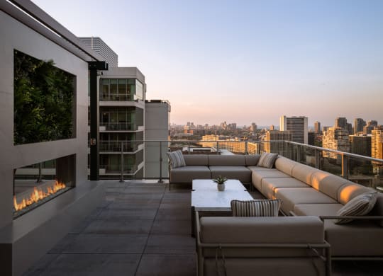 a terrace with couches and a fireplace overlooking a city