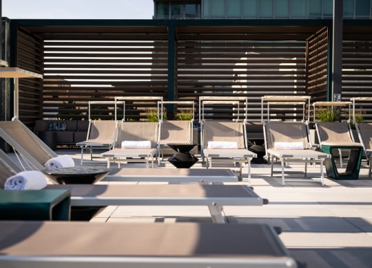 a row of lounge chairs on a patio with a building in the background