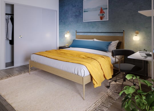 a bedroom with a bed with a yellow blanket and a blue and white painting on the wall