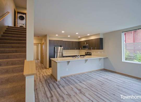 A spacious kitchen and living room with a staircase on the left side at Spyglass Hill Apartments, Bremerton, WA 98337