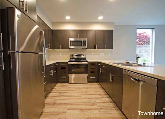 A kitchen with a stainless steel refrigerator and wooden floors at Spyglass Hill Apartments, Bremerton, WA 98337