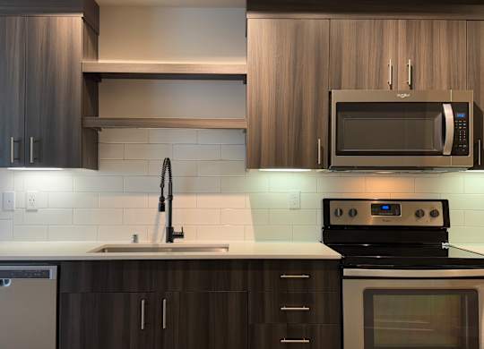 A modern kitchen with dark wood cabinets and a white countertop at B Flats Apartments, Bremerton, 98337