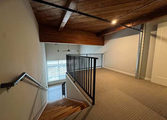 A room with a wooden ceiling and a staircase with a black railing at B Flats Apartments, Bremerton, 98337