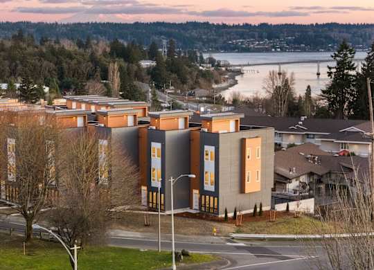 A building with a lot of windows is surrounded by trees. at The Narrows at Clare Apartments , Bremerton, Washington
