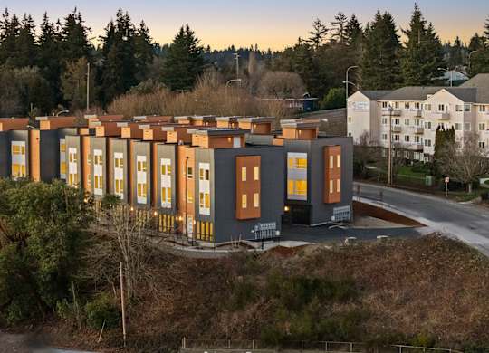 A modern building with a row of windows is surrounded by trees. at The Narrows at Clare Apartments , Apartments, Bremerton, WA