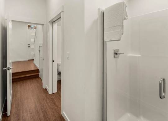 A white bathroom with a towel hanging on the door. at The Narrows at Clare Apartments , Washington