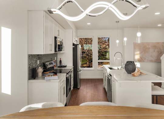 A modern kitchen with a wooden table and a refrigerator. at The Narrows at Clare Apartments , Apartments, Bremerton, WA