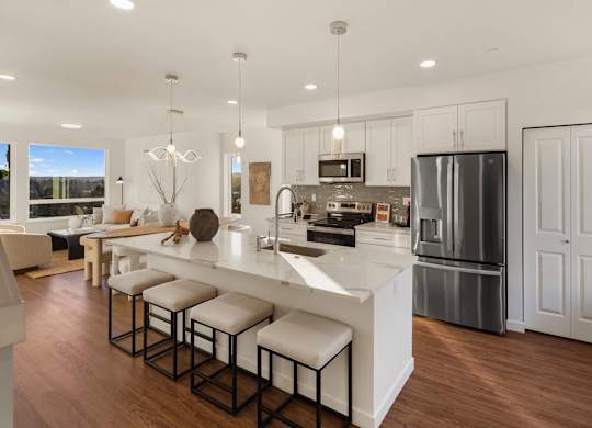 A modern kitchen with a bar stool and a refrigerator. at The Narrows at Clare Apartments , Bremerton
