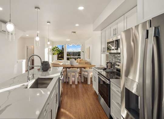 A modern kitchen with stainless steel appliances and white countertops. at The Narrows at Clare Apartments , Washington