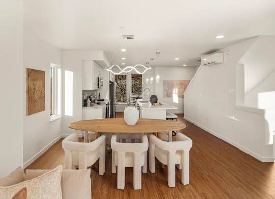 A dining room with a wooden table and white chairs. at The Narrows at Clare Apartments , Bremerton, Washington