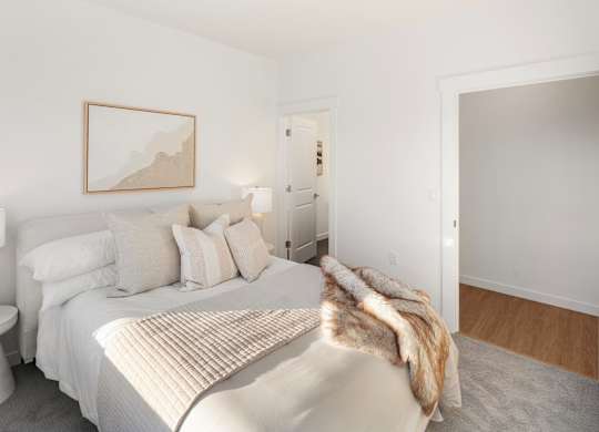 A bedroom with a bed, pillows, a lamp, and a painting on the wall. at The Narrows at Clare Apartments , Bremerton, WA, 98310