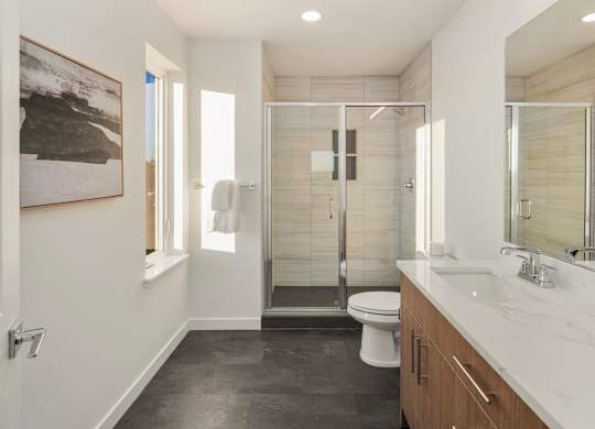 A bathroom with a toilet, sink, and shower. at The Narrows at Clare Apartments , Bremerton