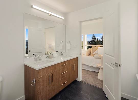 A bathroom with a large mirror, a white sink, and a white bathtub at The Narrows at Clare Apartments , Bremerton, Washington