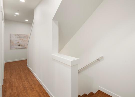 A white wall with a brown floor and a white staircase. at The Narrows at Clare Apartments , Bremerton, Washington