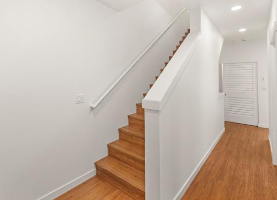 A wooden staircase with white walls and a white door. at The Narrows at Clare Apartments , Bremerton, WA, 98310
