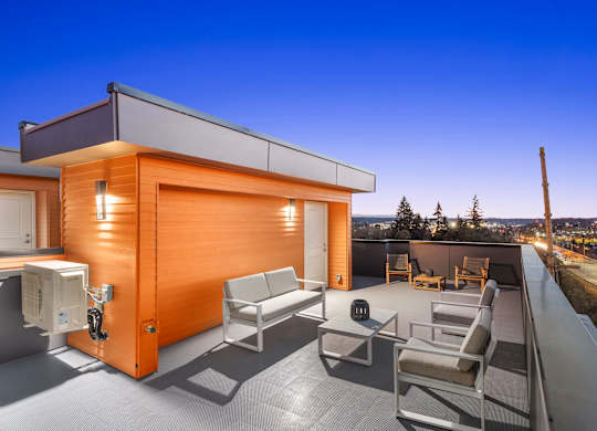 A modern house with a wooden exterior and a patio with chairs and a couch at The Narrows at Clare Apartments , Apartments, Bremerton, WA