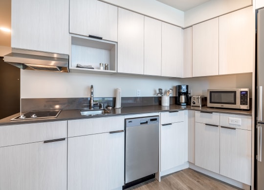 a kitchen with white cabinets and stainless steel appliances at Marina Square, Bremerton, WA