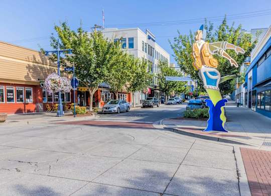 A large blue and yellow sculpture of a person is in the middle of a street.