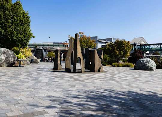 A park with a large rock and a bridge in the background.