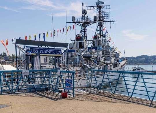 A large ship named USS Turner Joy is docked at a pier.