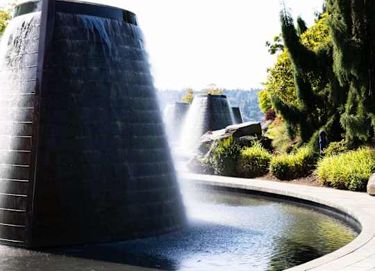 A water fountain with a tall, dark structure shooting water upwards.