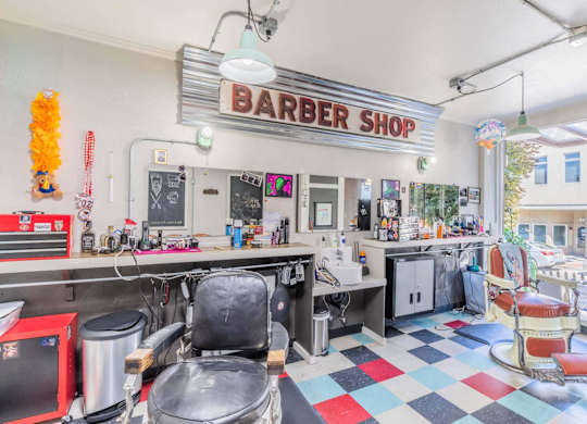 A barber shop with a checkered floor and a red and black chair.