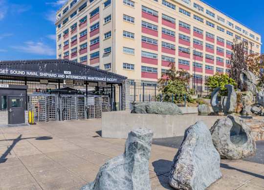 A large rock formation sits in front of a building with a sign that reads