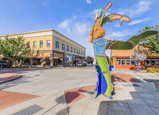 A large, colorful sculpture of a bird is situated in the middle of a city square.