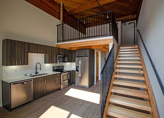 A modern kitchen with a staircase leading to the upper floor at B Flats Apartments, Bremerton, Washington