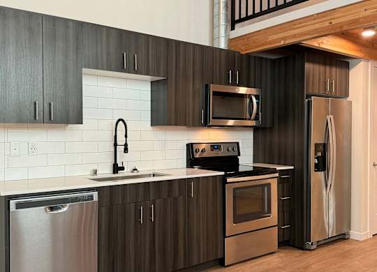 A modern kitchen with dark wood cabinets and stainless steel appliances at B Flats Apartments, Bremerton, WA