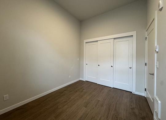 A room with white walls and wood flooring with a white door at B Flats Apartments, Bremerton, Washington