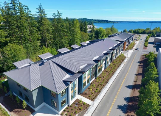 an aerial view of a building with a metal roof and a lake in the background at Rivulet, Silverdale, 98383