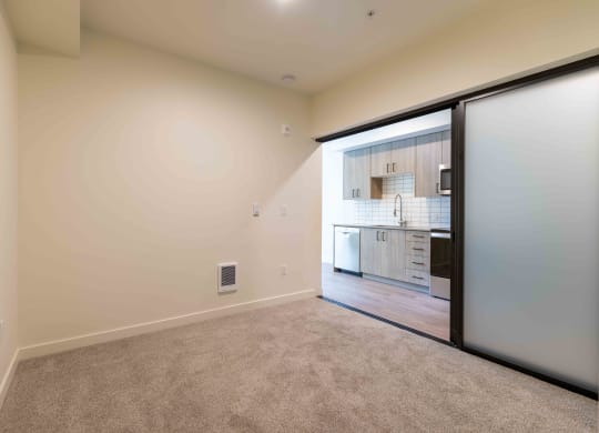 a room with a door to a kitchen and a carpeted floor at Rivulet, Washington, 98383