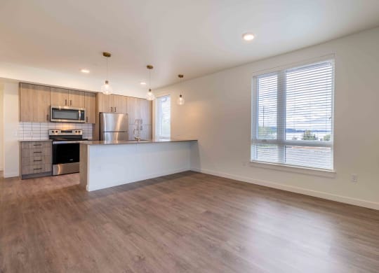 an empty living room with a kitchen and a large window at Rivulet, Washington, 98383