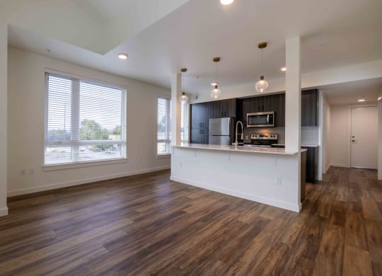 an empty living room with a kitchen and a large window at Rivulet, Silverdale, WA