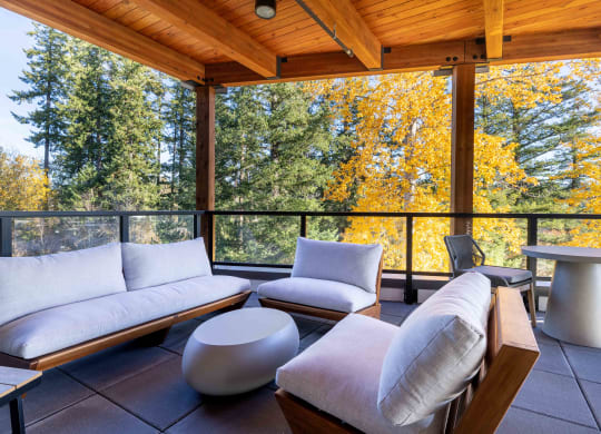 a covered porch with couches and chairs and a view of trees at Rivulet, Silverdale, 98383