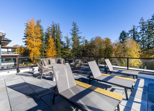 a patio with chairs and tables on a balcony with trees at Rivulet, Silverdale, 98383