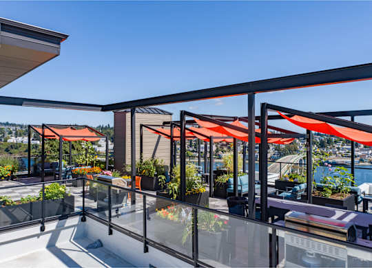 a terrace with orange umbrellas and tables on a balcony overlooking the water at Spyglass Hill Apartments, Bremerton, WA