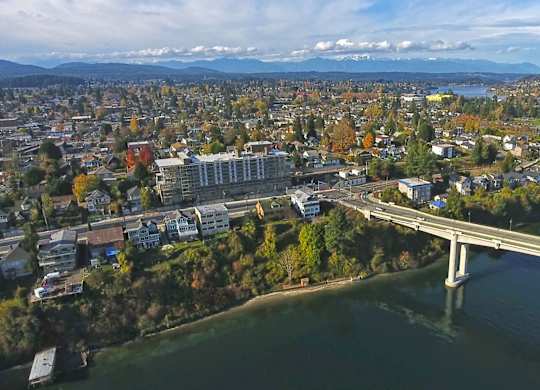 A bridge crosses a river in a city with buildings and trees at Spyglass Hill Apartments, Bremerton, WA