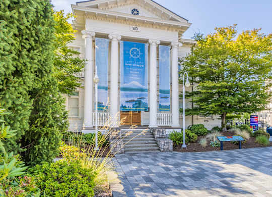 A white building with a banner on the front and a tree in front of it.