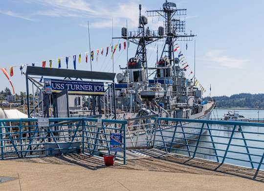 A large ship named USS Turner Joy is docked at a pier.