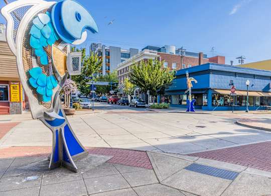 A blue and white bird sculpture is in the foreground of a city square.