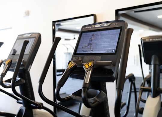 A row of stationary bikes in a gym. at The Crest at Oakwood Apartments, Georgia, 30566