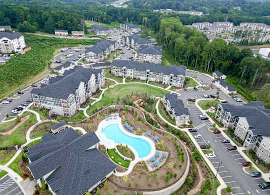 Aerial view of The Crest at Oakwood apartment buildings, swimming pool and landscaped grounds in Oakwood, GA.
