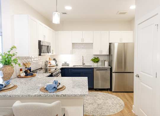 Kitchen with stainless steel appliances, white cabinetry and breakfast bar at The Crest at Oakwood apartments in Oakwood, GA.