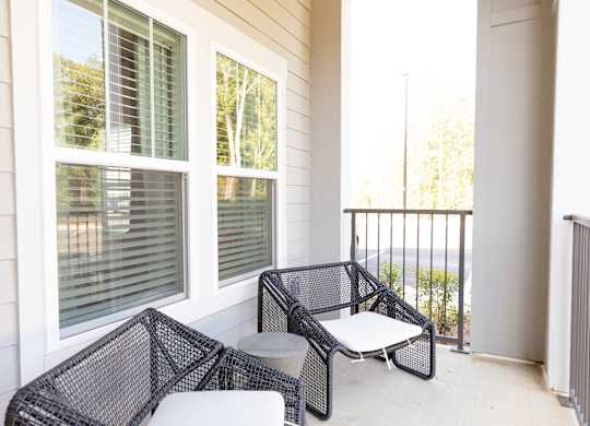 Patio with outdoor seating and a railing at a two-bedroom model apartment at The Crest at Oakwood in Oakwood, GA.